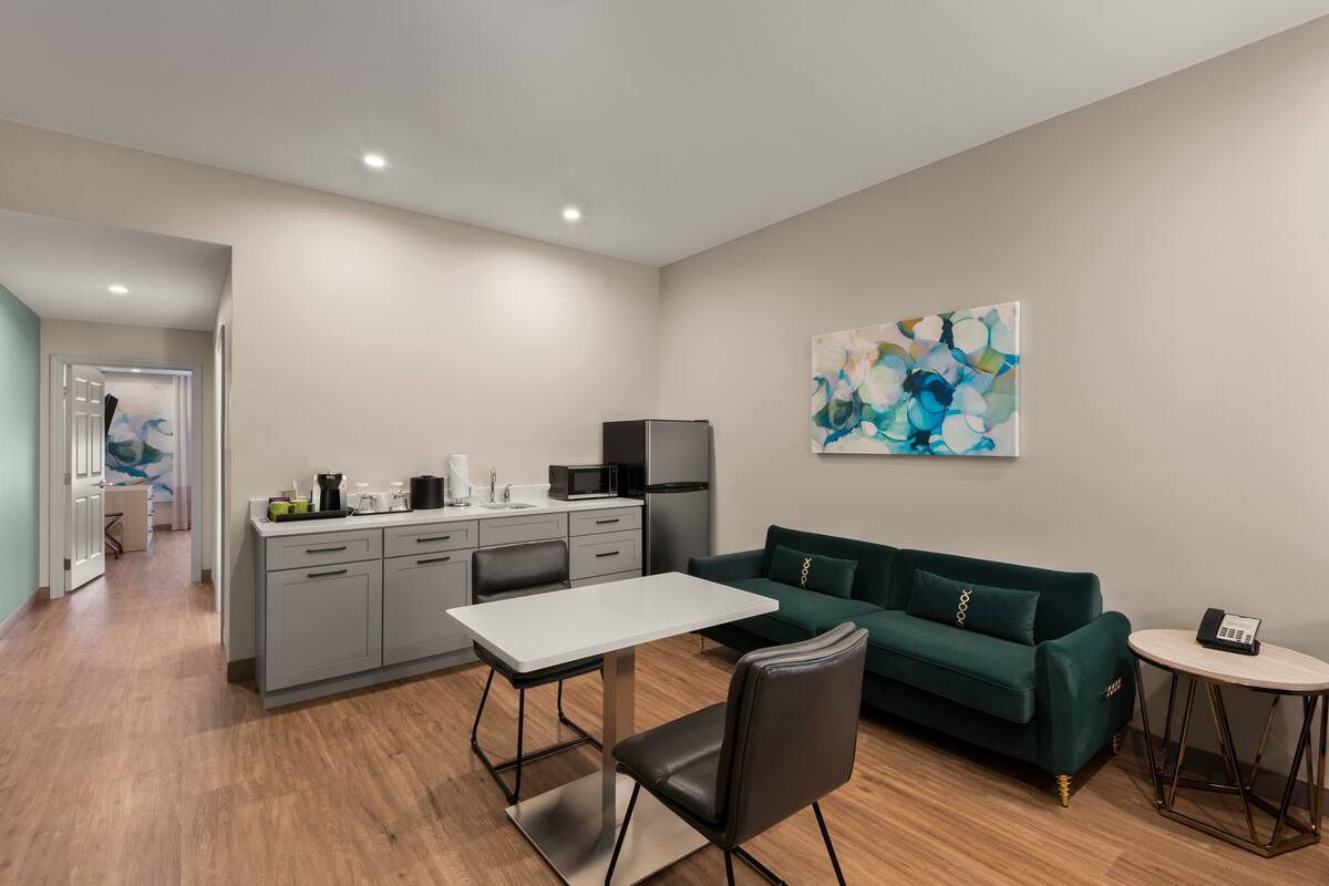 Una cocina moderna con gabinetes grises, una encimera blanca y una zona de comedor con una mesa y sillas.