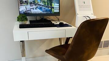 A modern office setup with a white desk, a computer monitor, a keyboard, a mouse, a brown office chair, and a charging station.