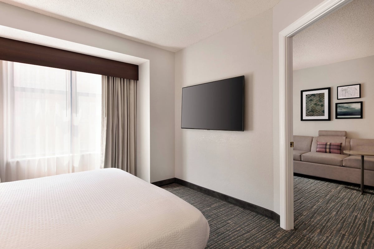 A hotel room with a large bed, a flat-screen TV, a sofa, and a small table.