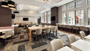 A modern dining area with a large wooden table, multiple chairs, and pendant lighting. - Residence Inn by Marriott Baltimore Inner Harbor (Baltimore)
