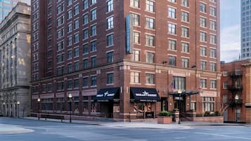 A multi-story hotel with a brick facade, sports bar & grill on the ground floor, and a flag outside.