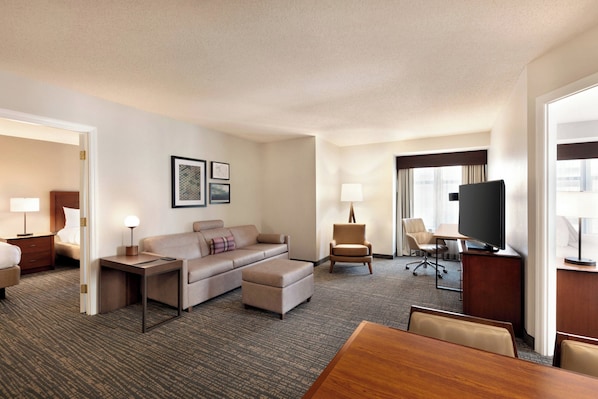 A hotel room with a sofa, armchair, TV, desk, and a dining table. - Residence Inn by Marriott Baltimore Inner Harbor (Baltimore)