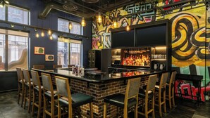 Eine Barbereich mit einer Ziegel-Theke, Barhocker und einer Wand mit Graffiti.