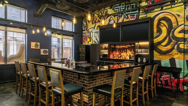 A bar area with a brick counter, bar stools, and a graffiti wall. - Residence Inn by Marriott Baltimore Inner Harbor (Baltimore)