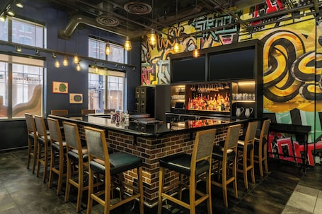 A bar area with a brick counter, bar stools, and a graffiti wall.. Residence Inn by Marriott Baltimore Inner Harbor