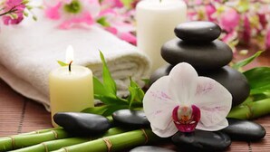 A spa setting with a white towel, two candles, a stack of smooth stones, and an orchid. - Crowne Plaza Shanghai Pudong by IHG (Shanghai)