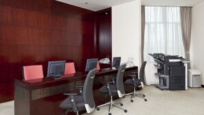 A conference room with a dark wood panel wall, a long table with four black office chairs, and a printer station. - Crowne Plaza Shanghai Pudong by IHG (Shanghai)