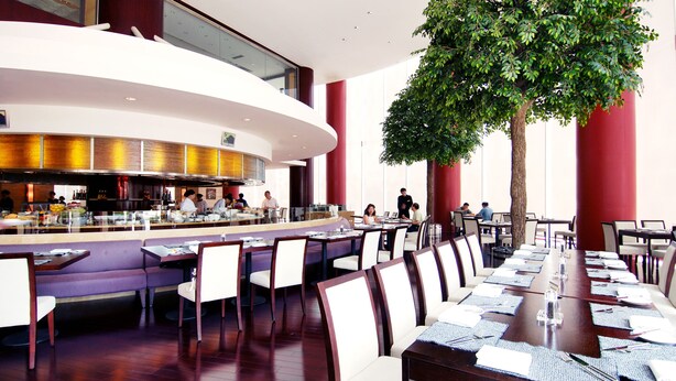 A modern restaurant with a central bar, dining tables, and chairs arranged for service. - Crowne Plaza Shanghai Pudong by IHG (Shanghai)