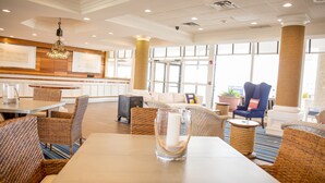 A spacious lobby with wicker furniture, a large window, and a chandelier. - Port Royal Oceanfront Hotel (Wildwood Crest)