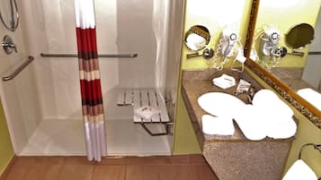 Ein Badezimmer mit Dusche, Waschtisch inklusive Spiegel und Handtuchhalter.