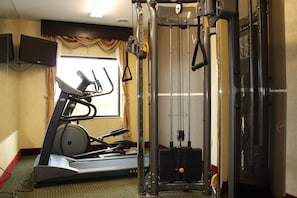 A gym with exercise equipment including a treadmill, weight machines, and a cable machine. - Red Roof Inn & Suites Detroit-Melvindale/ Dearborn (Melvindale)