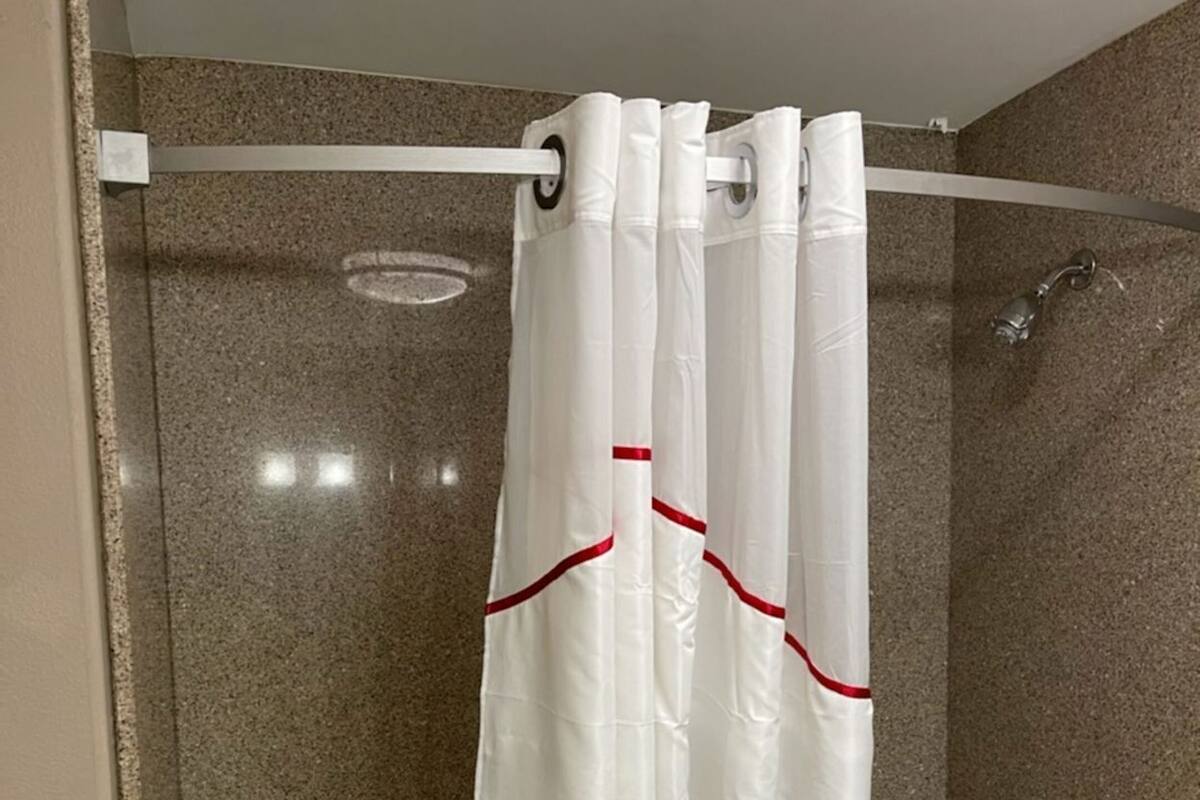 Ein Badezimmer mit Duschvorhang, Badewanne und Duschkopf.
