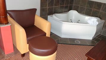 A bathroom with a bathtub, a chair, and a small stool.