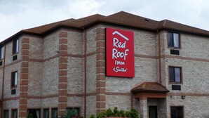 En byggnad som tillhör hotellkedjan Red Roof Inn & Suites, med en röd skylt, en fasad av tegel och flera fönster.