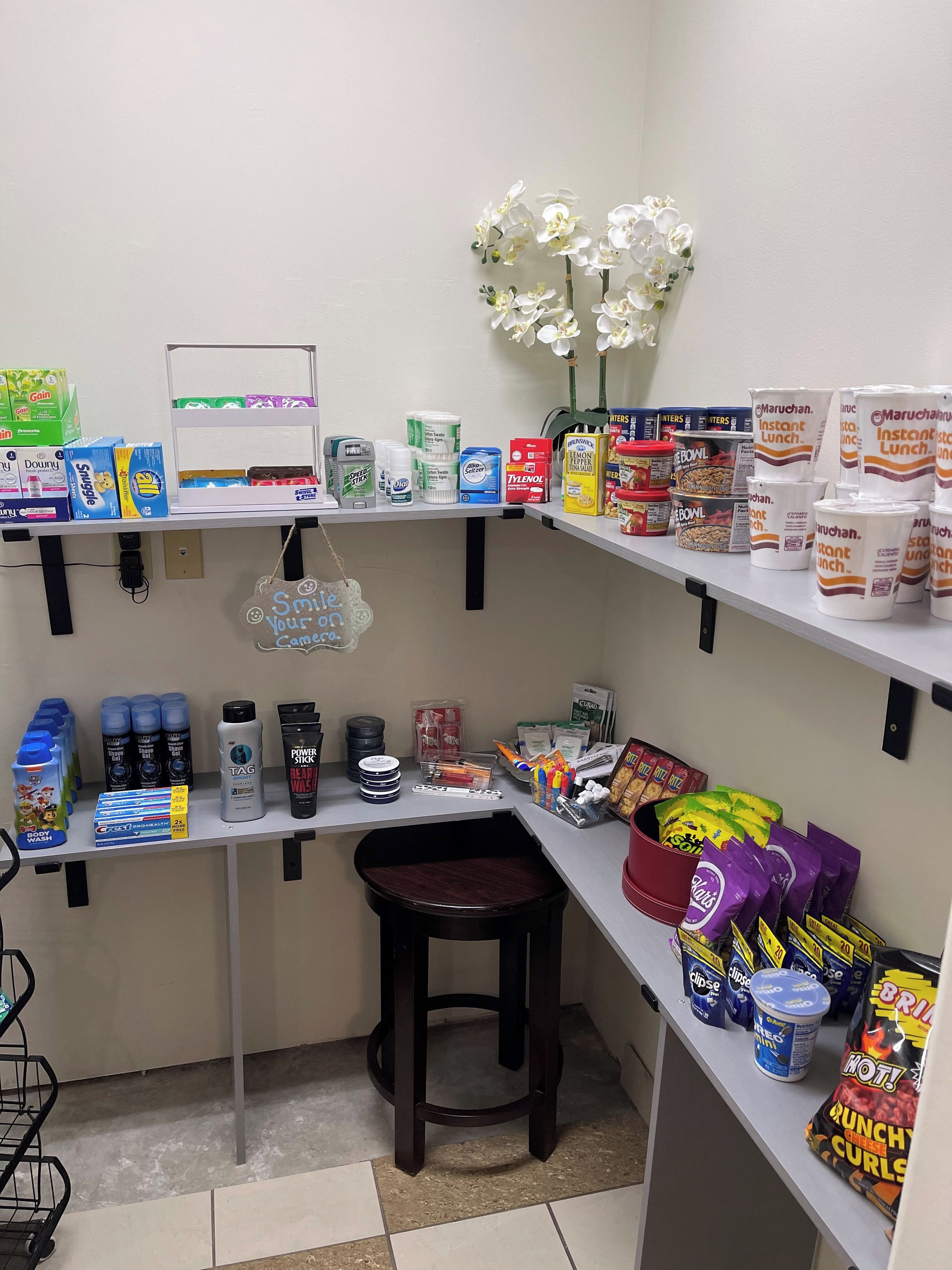 A kitchenette with shelves stocked with food items, a coffee machine, and a small stool.