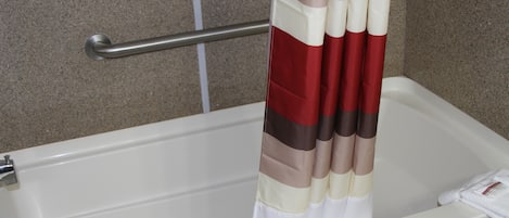 A bathroom with a bathtub, a metal grab bar, and a striped shower curtain.