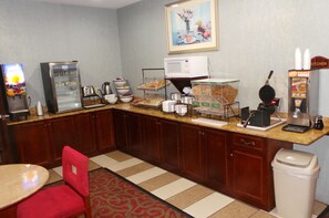 A hotel kitchen with a coffee machine, microwave, and various food items on display. - Red Roof Inn & Suites Detroit-Melvindale/ Dearborn (Melvindale)