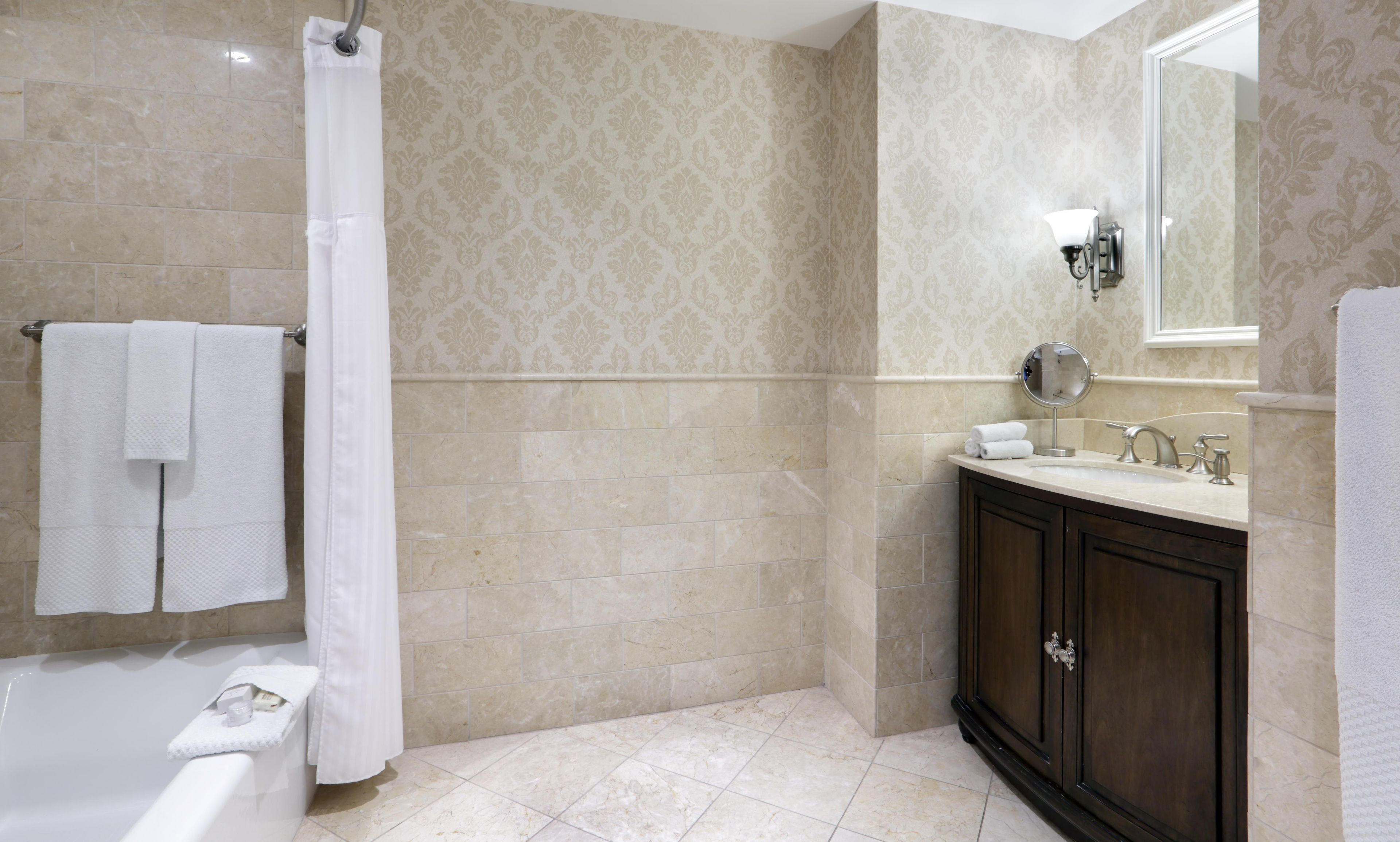 A bathroom with a bathtub, a shower curtain, a sink with a mirror, and a towel rack.