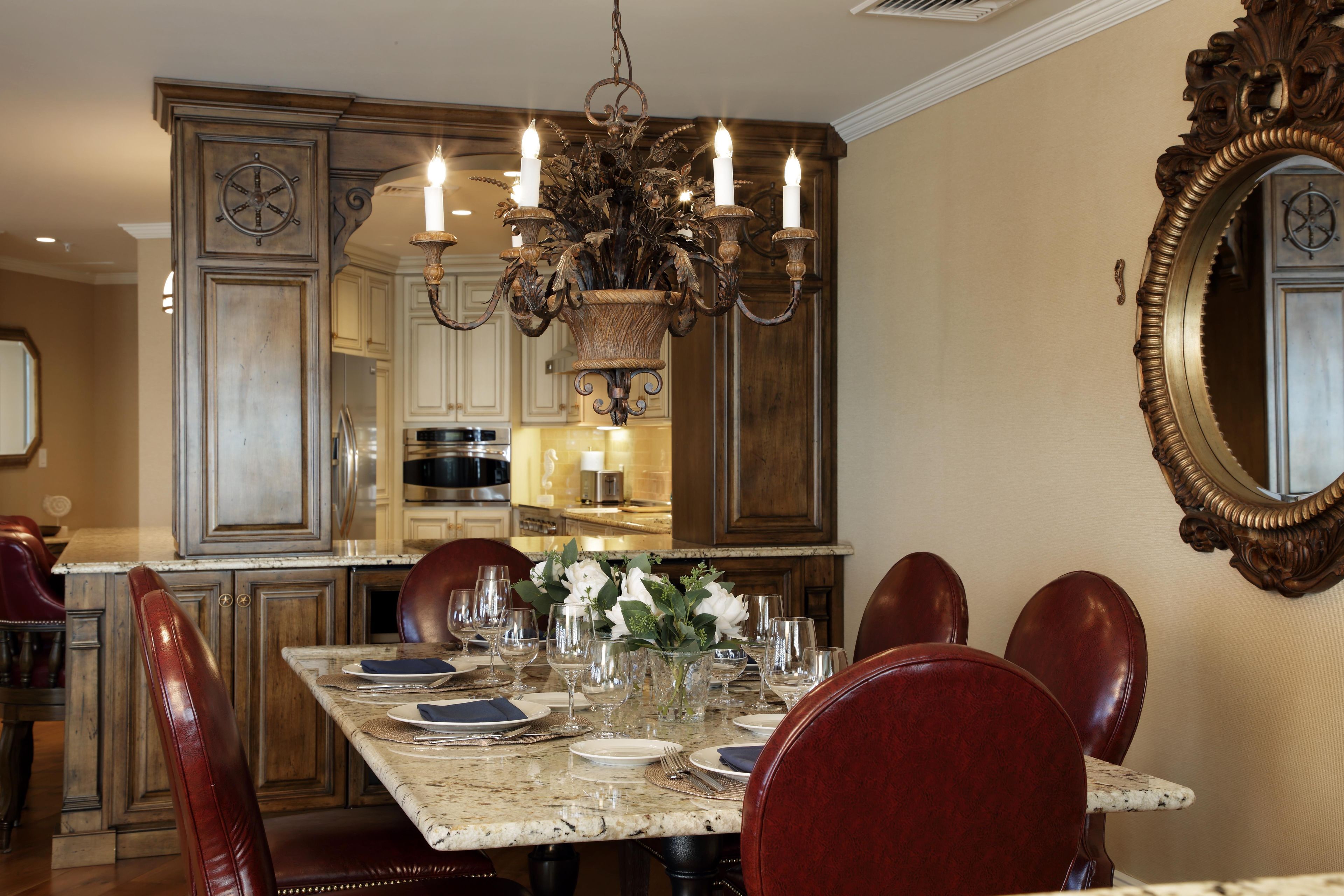 A dining area with a marble table set for six, surrounded by red upholstered chairs.