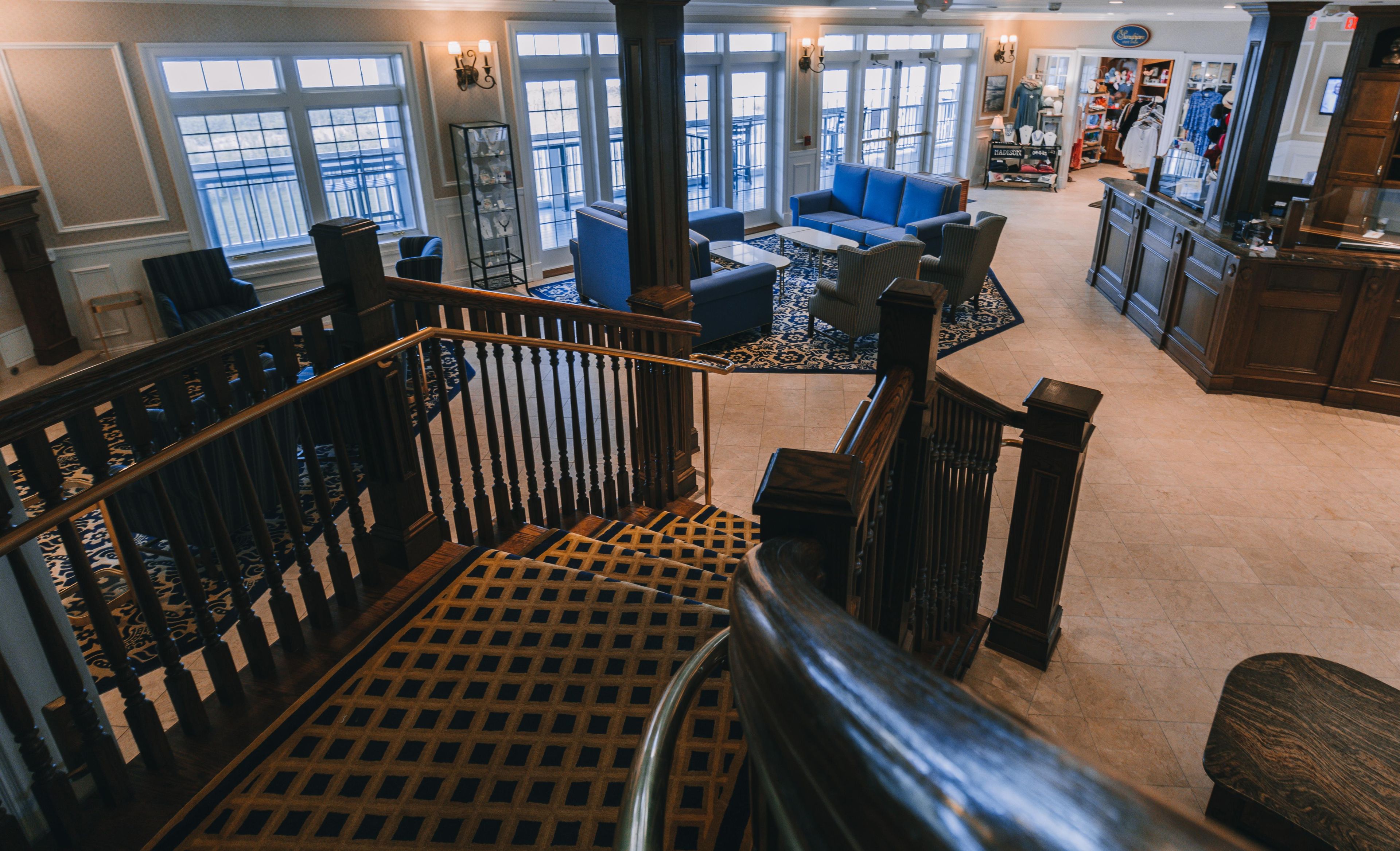A spacious interior with a staircase, a seating area, and a view of the outside through large windows.