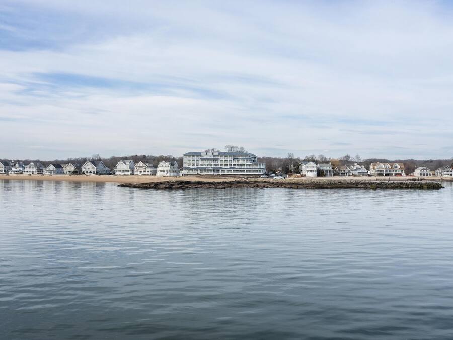 A waterfront property with a large building, a dock, and a row of houses along the shore.