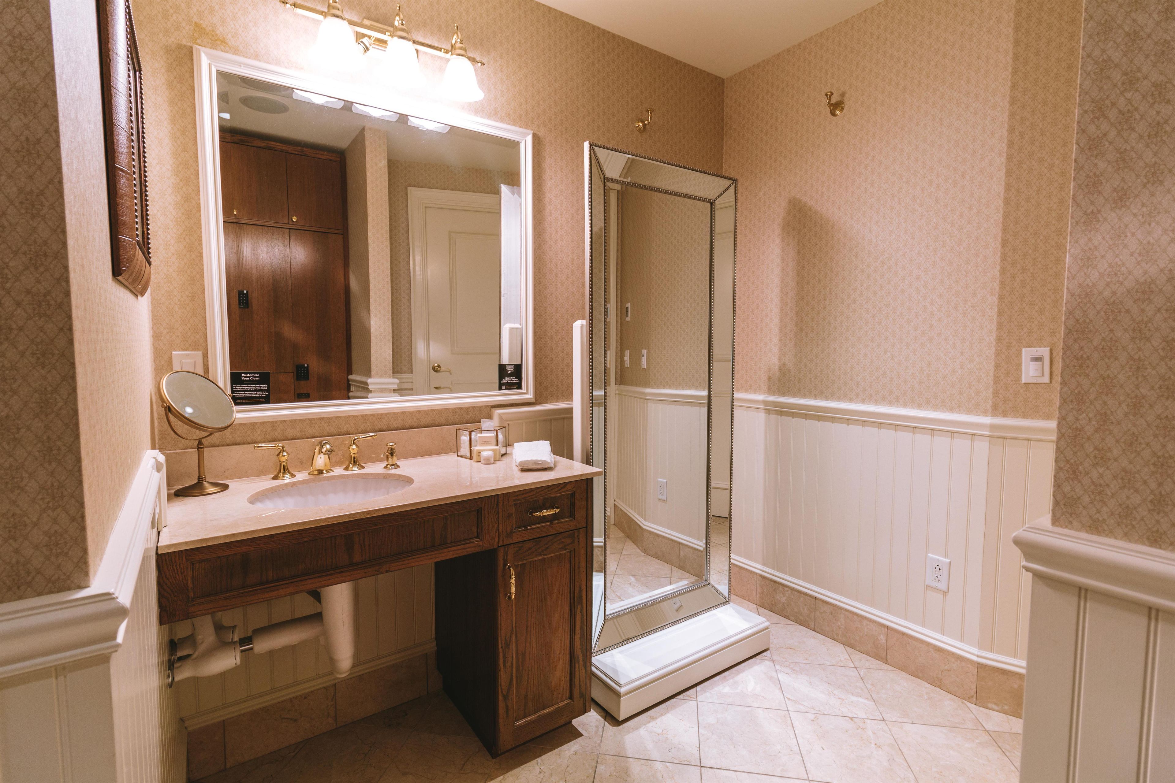 Une salle de bain avec un grand miroir, un lavabo, un meuble-lavabo et un espace douche.