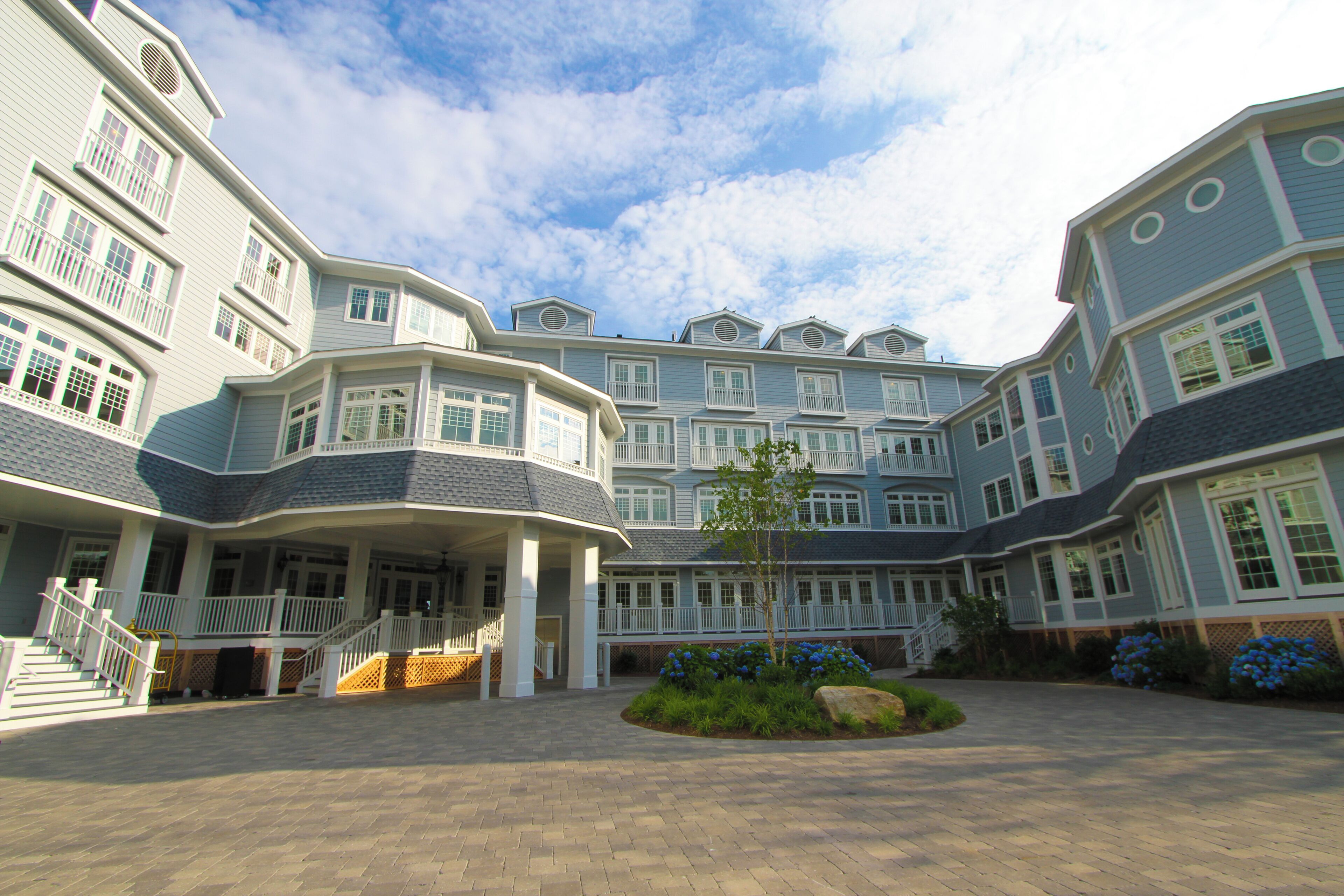 A large, multi-story hotel with a central courtyard, multiple balconies, and a well-maintained garden area.