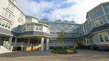 A large, multi-story hotel with a central courtyard, multiple balconies, and a well-maintained garden area.