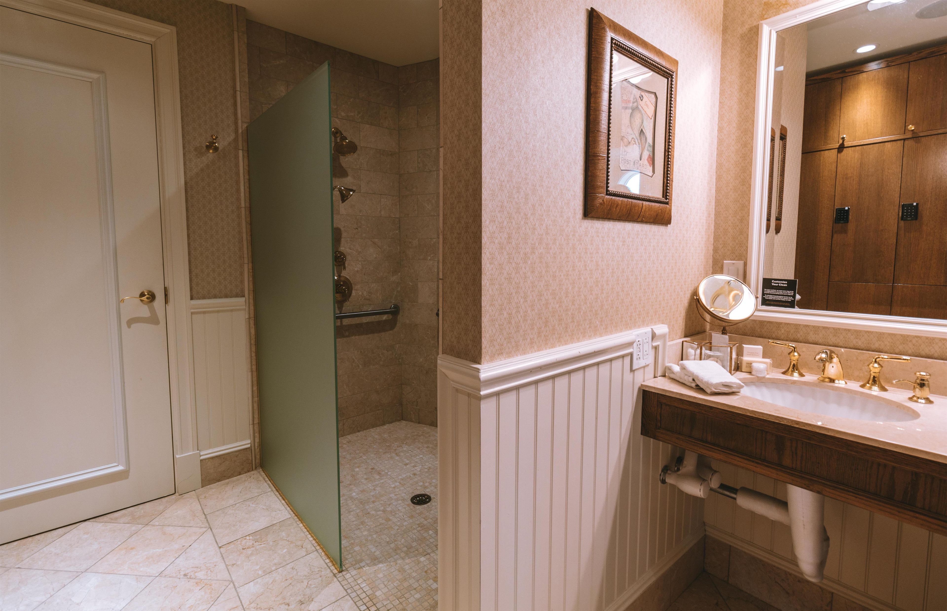 A bathroom with a shower, a sink with a mirror, and a door.