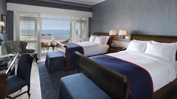 Une chambre d’hôtel avec un grand lit, deux tables de chevet, un bureau avec un ordinateur portable, une chaise et un balcon avec vue.