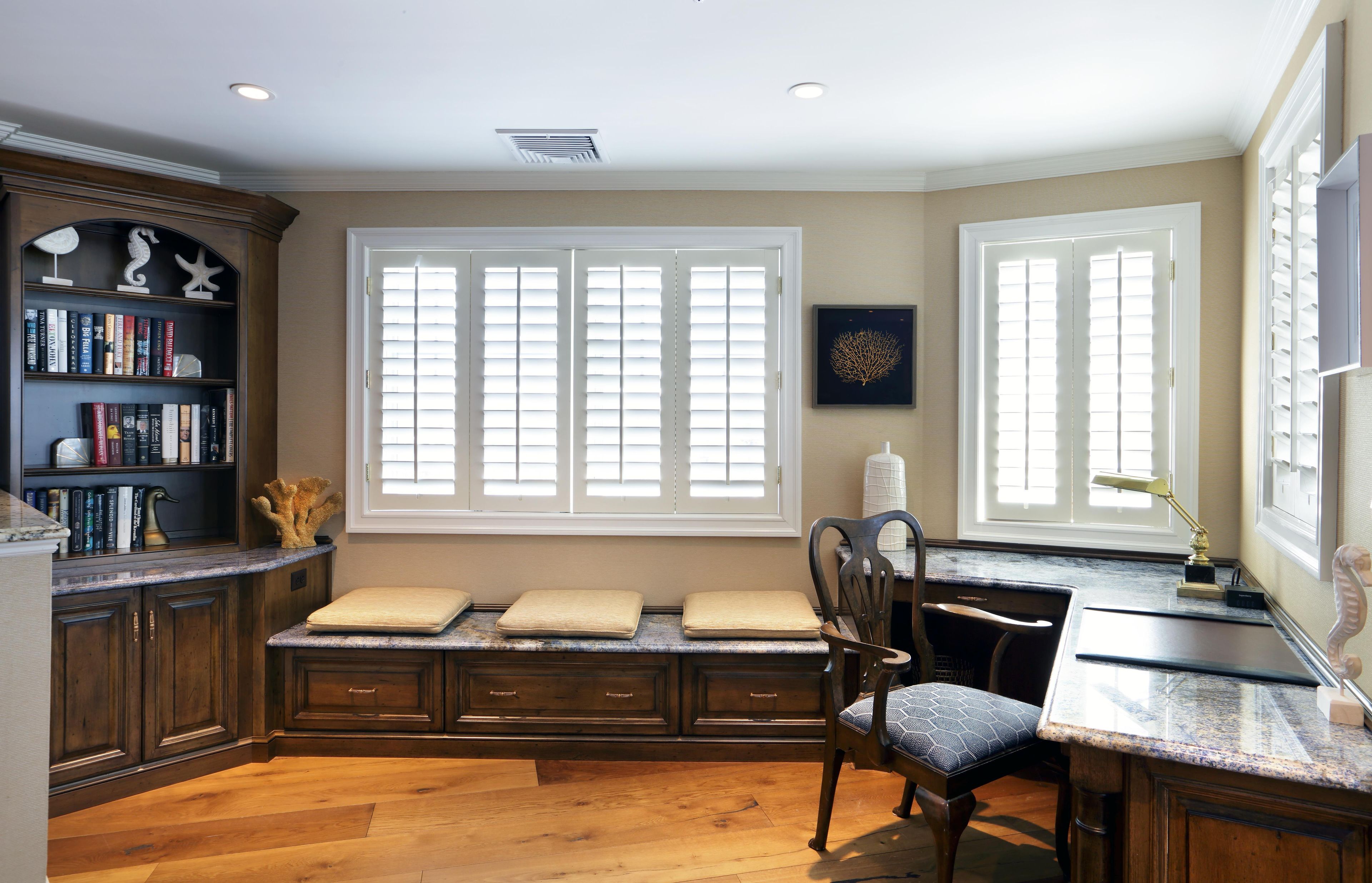 A well-lit room with a built-in bench, a desk, and a bookshelf.