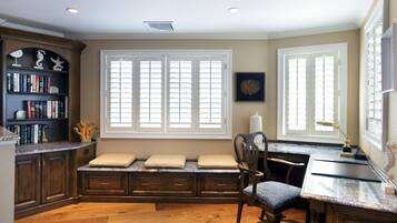 A well-lit room with a built-in bench, a desk, and a bookshelf.