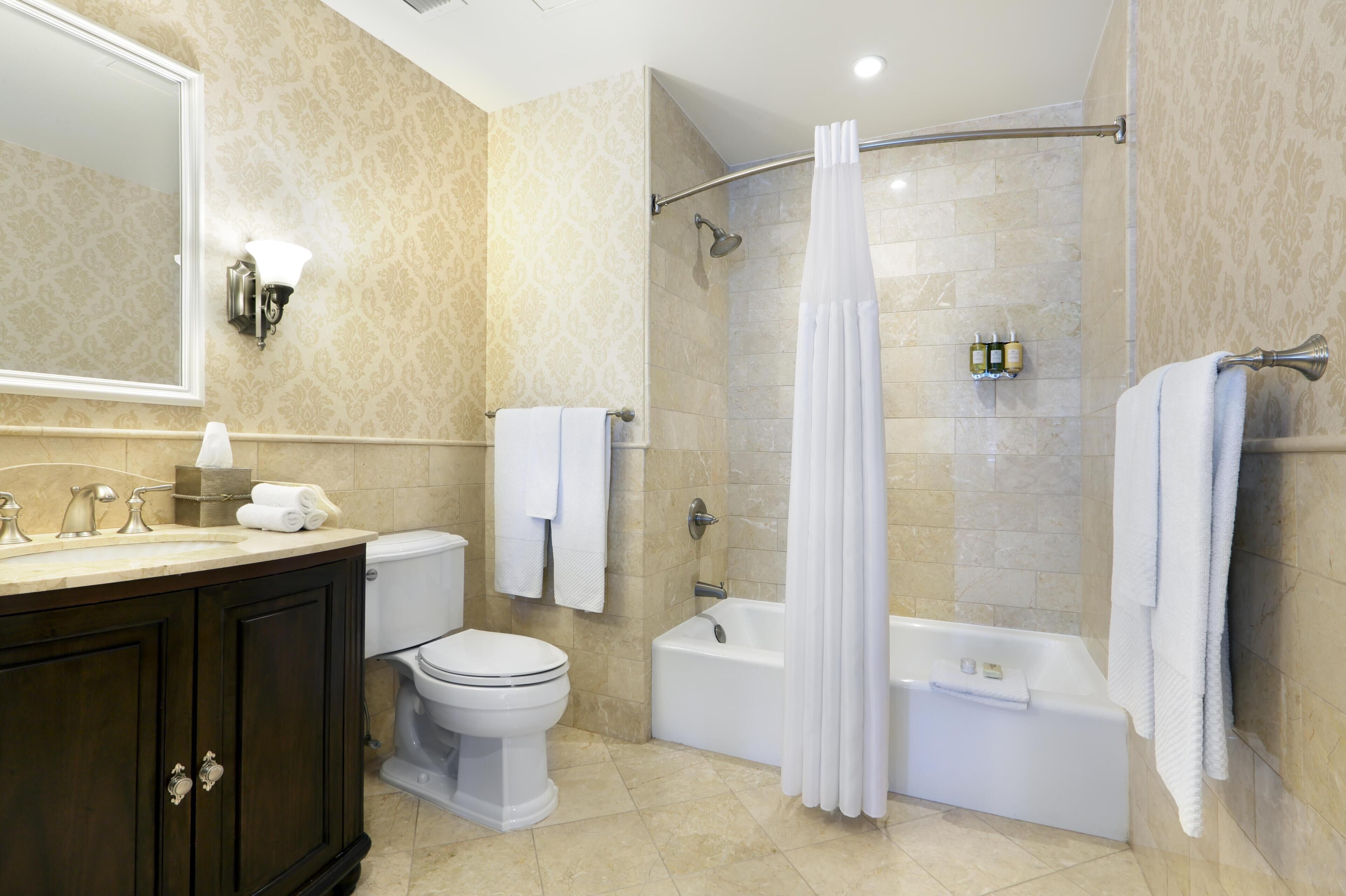 A bathroom with a toilet, sink, bathtub, shower, and a large mirror.