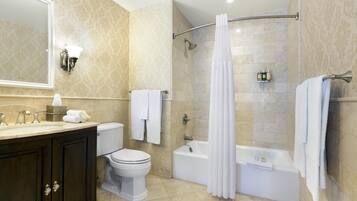 A bathroom with a toilet, sink, bathtub, shower, and a large mirror.