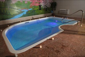 An indoor swimming pool with a mural of a landscape and a bridge, a metal ladder, and candles on the floor. - Belamere Suites Hotel (Perrysburg)