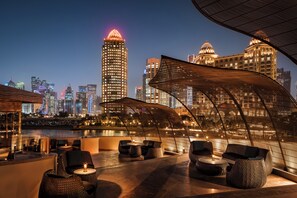 A rooftop lounge with seating and a view of a city skyline at night. - Four Seasons Hotel Doha (Doha)