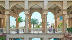 A pool area with a stone archway, palm trees, and a clear blue pool. - Four Seasons Hotel Doha (Doha)