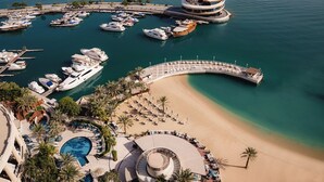 A marina with boats, a beach, and a pool area. - Four Seasons Hotel Doha (Doha)