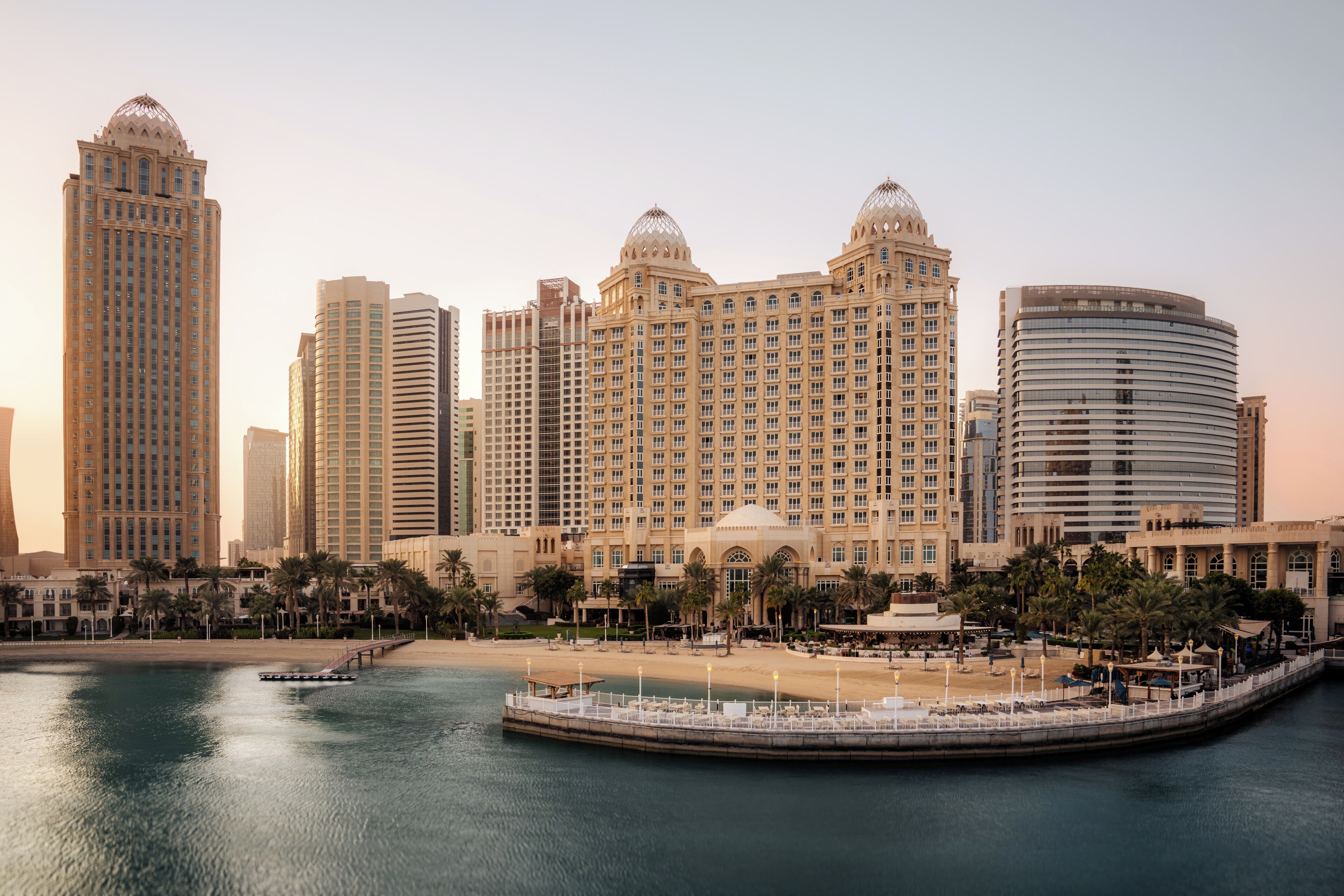 Een kuststadsgezicht met hoge hotels, een waterpromenade en palmbomen.