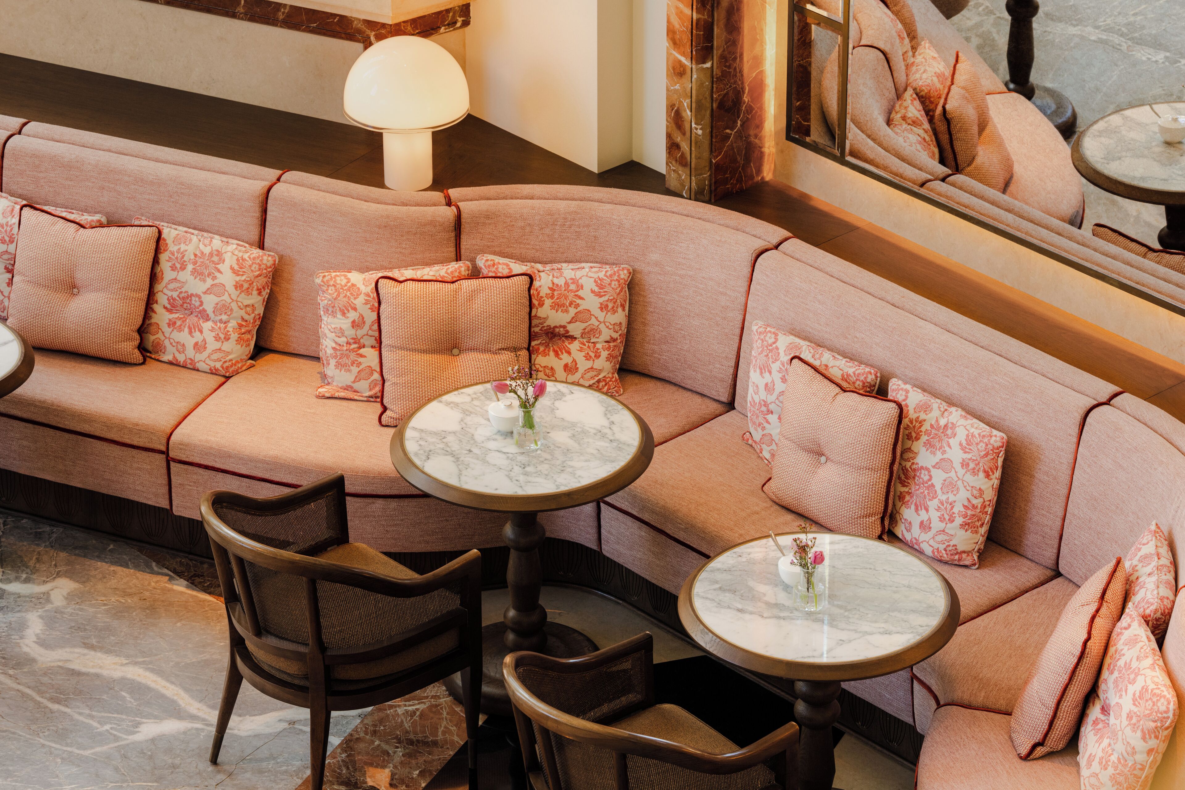 A corner seating area with a sofa, two round tables, and chairs.