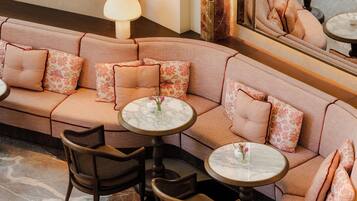 A corner seating area with a sofa, two round tables, and chairs.
