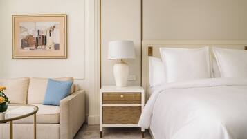 Une chambre d’hôtel avec un lit, une table de chevet avec une lampe, un canapé et un tableau encadré au mur.