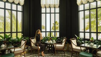 Una habitación con ventanas amplias, una mesa con sillas y plantas en macetas.