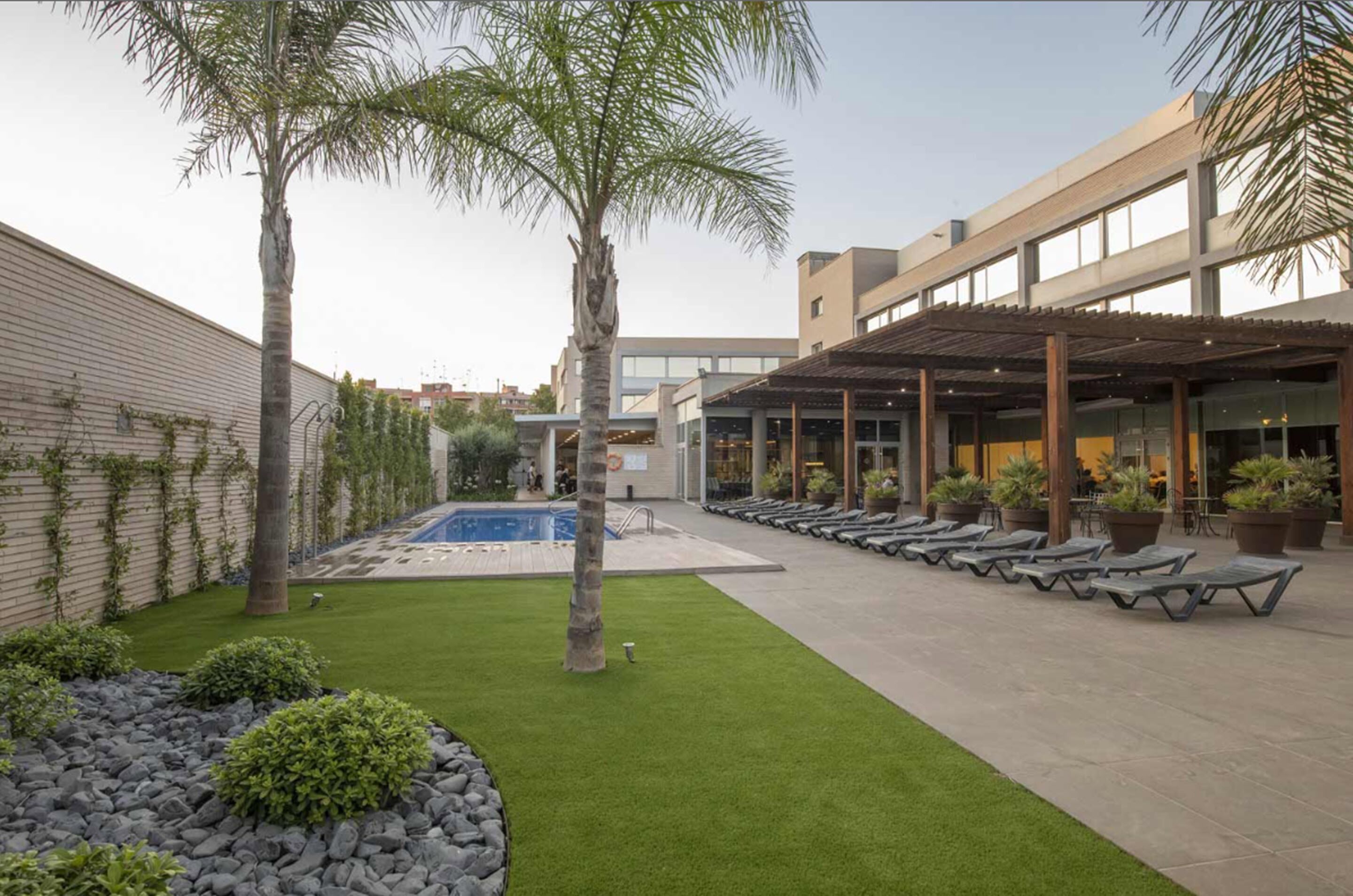 Un patio con piscina, sillones de descanso y una zona de estar cubierta.