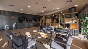 Um lobby moderno com balcão de recepção, área de estar e plantas em vasos.