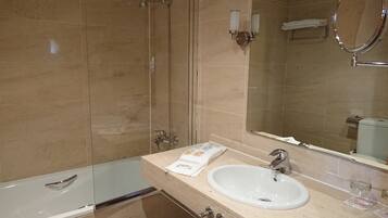 A modern bathroom with a glass-enclosed shower, a white sink, and a large mirror.