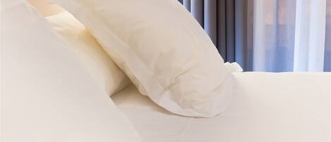 A neatly made bed with white bedding and pillows.