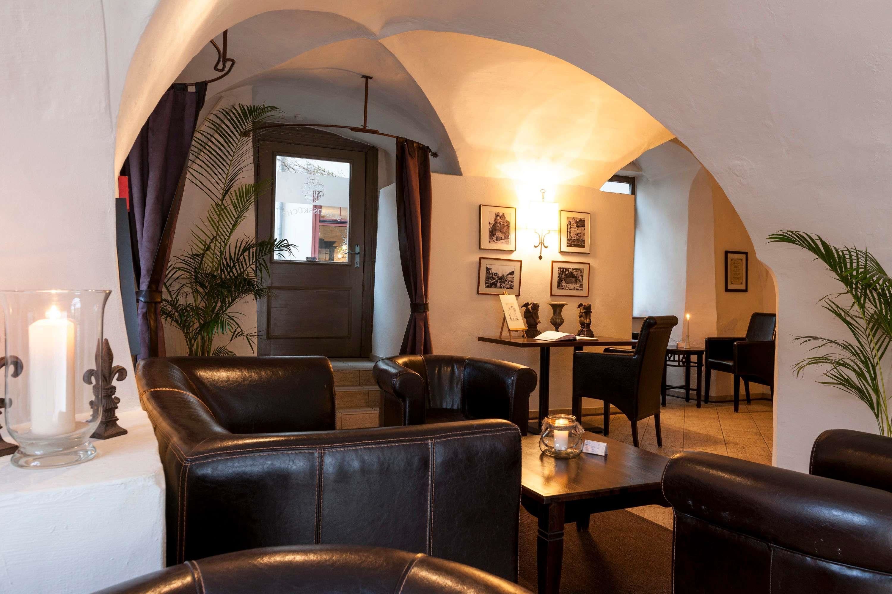 A cozy restaurant with leather seating, a lit candle centerpiece, and framed pictures on the walls.