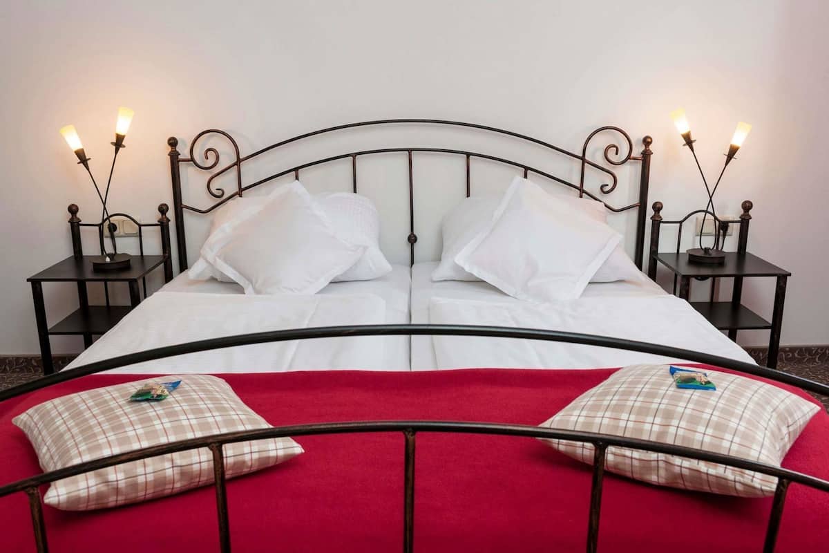 A bed with white bedding, two bedside tables with lamps, and a red blanket.