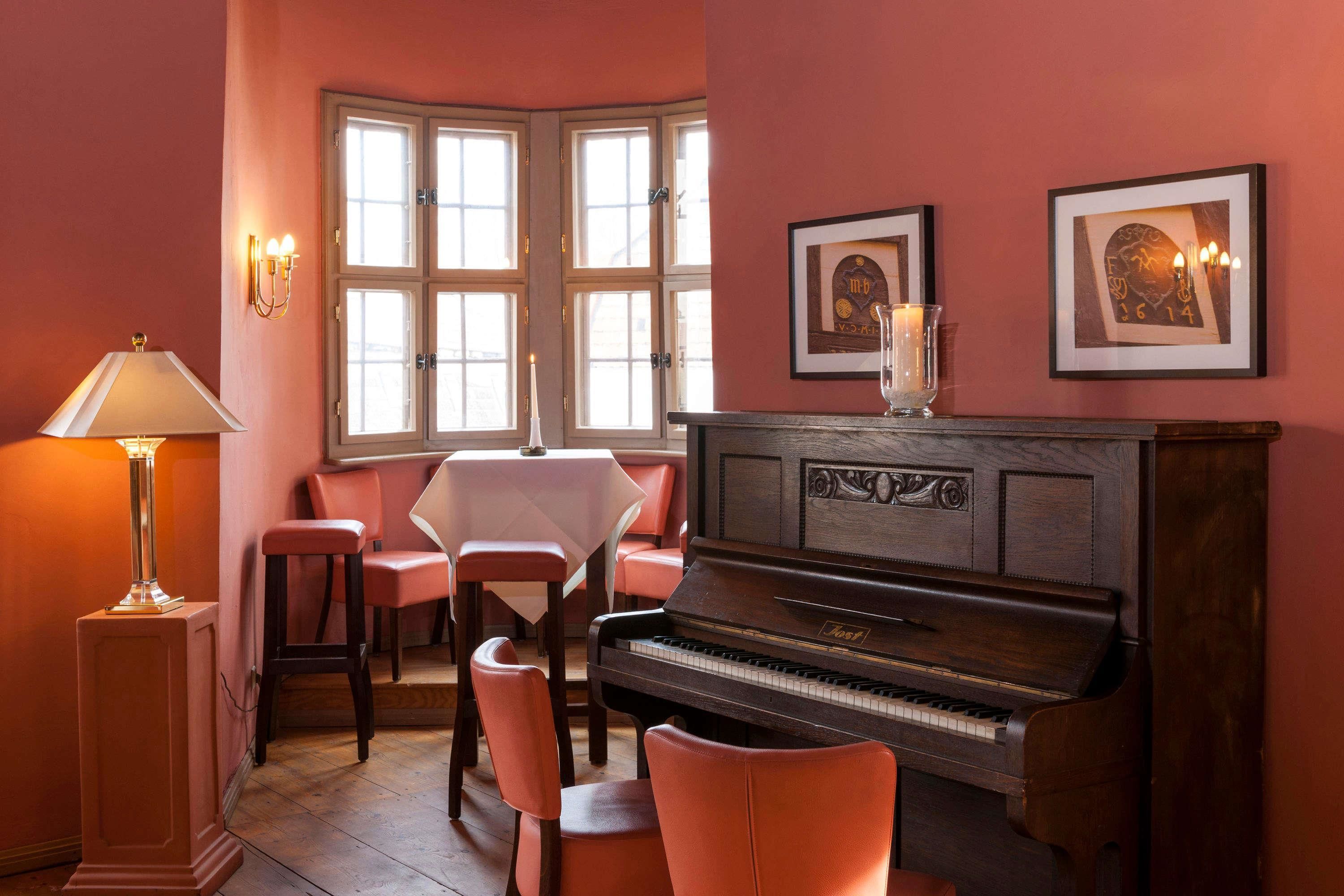 A cozy room with a piano, a table, and chairs.